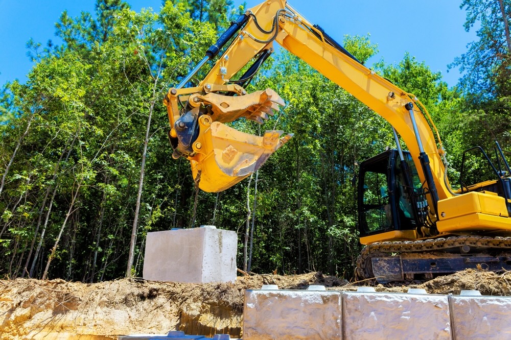 Yellow excavator working beside concrete blocks at a wooded construction site - land clearing in louisiana - cypress line services