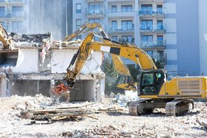 Yellow excavators removing a concrete building beside an apartment complex - excavation in baton rouge